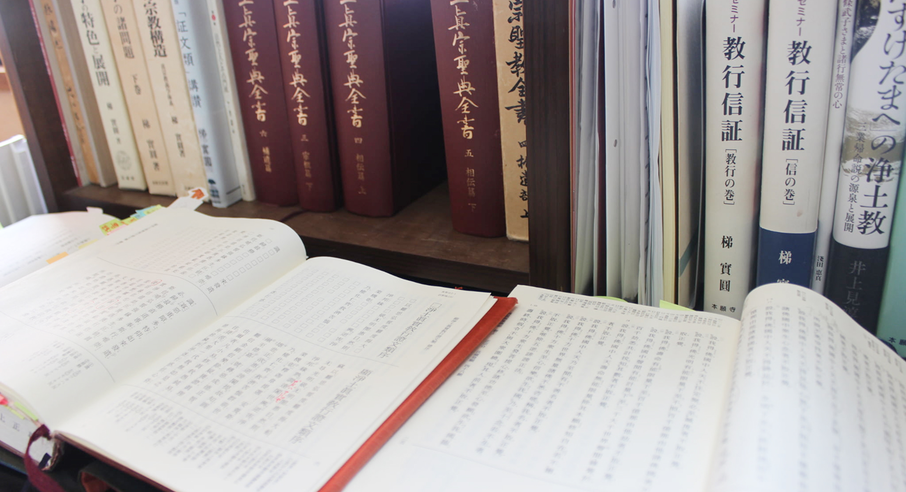 本棚に並ぶ仏教書と開かれた経典の画像